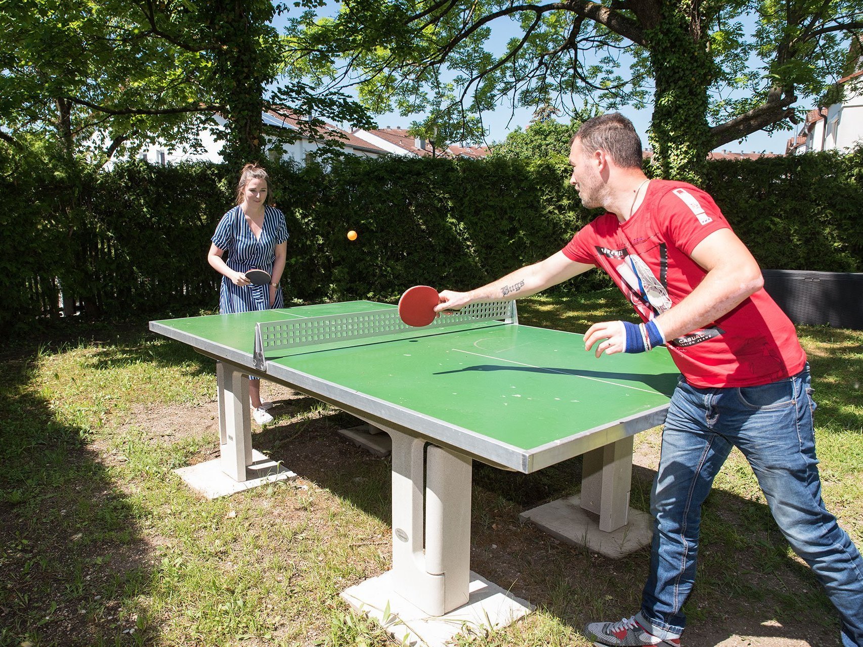 eine junge Frau und ein junger Mann im Garten beim Tischtennis